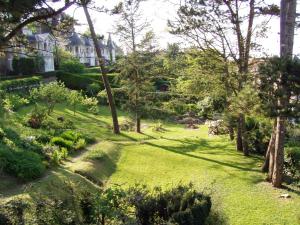 einen Garten mit Bäumen und Gras und ein Haus in der Unterkunft La Villa Marguerite in Pourville-sur-Mer