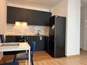 a kitchen with a black refrigerator and a table at Apartament Porto Seaside in Gdańsk