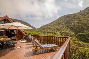 a deck with a table and chairs and an umbrella at Ballots Bay Treehouse by Host Agents in George