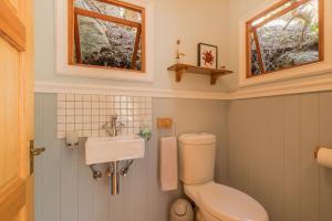 a bathroom with a toilet and a sink and two windows at Ballots Bay Treehouse by Host Agents in George