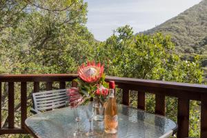 a glass table with a bottle of wine and flowers at Ballots Bay Treehouse by Host Agents in George