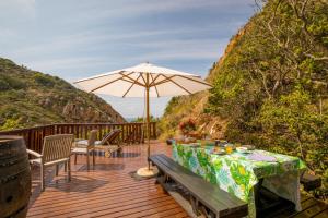 a wooden deck with a table and an umbrella at Ballots Bay Treehouse by HostAgents in George