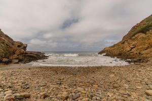 a rocky beach with waves crashing on the shore at Ballots Bay Treehouse by Host Agents in George