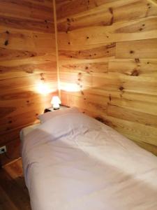 ein Schlafzimmer mit einem weißen Bett an einer Holzwand in der Unterkunft Gite de caractère rural in Bastogne