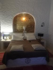 a bedroom with a large bed with a brick wall at Riad Dar El Caid - Palais XIII Siecle in Tozeur