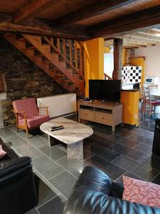 ein Wohnzimmer mit einem Sofa, einem TV und einem Tisch in der Unterkunft Gite de caractère rural in Bastogne