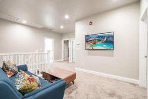 ein Wohnzimmer mit einem blauen Sofa und einem TV an der Wand in der Unterkunft Zion Village Poolhouse in Hurricane with Pool and Hot Tub in Hurricane