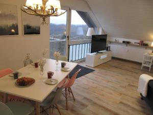 - un salon avec une table, des chaises et une télévision dans l'établissement Sperrentalblick, à Sankt-Andreasberg