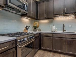 una cocina con electrodomésticos de acero inoxidable y armarios de madera en Sage Creek E3 in Moab with Private Hot Tub and Community Pool en Moab