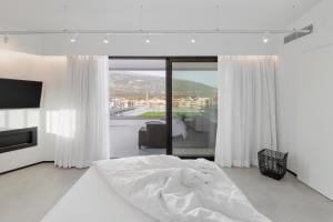 a white bedroom with a bed and a large window at No Stars - Luxury Hotel Apartments in Ioannina