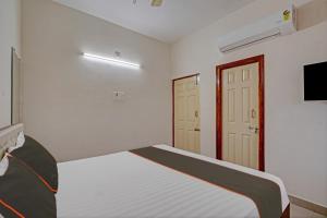 a white bedroom with a bed and a television at Collection O Ns Service Apartment in Tirupati