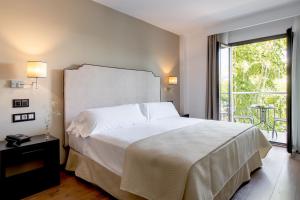 a bedroom with a large white bed and a balcony at Hotel Infanta Leonor in Écija
