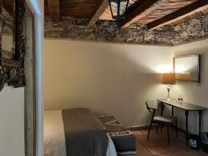 ein Schlafzimmer mit einem Bett und einem Schreibtisch mit einer Lampe in der Unterkunft Hotel Amor y Paz in Real de Catorce