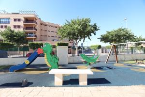 een park met een speeltuin met een glijbaan en een bank bij Ático con piscina en excelente urbanización by Hometels in Canet de Berenguer