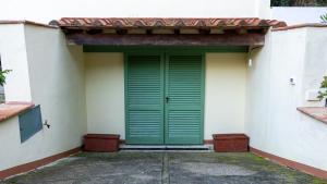 a green door on the side of a building at Bilocale a due passi dal mare immerso nel verde in Castiglioncello