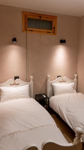 2 weiße Betten nebeneinander in einem Zimmer in der Unterkunft Bilocale a due passi dal mare immerso nel verde in Castiglioncello
