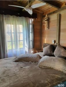 um quarto com uma cama grande em frente a uma janela em Chalé Cafofo em Campo Alegre