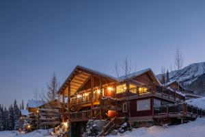 een groot houten huis in de sneeuw bij zonsondergang bij Lush Mountain Accommodations in Golden