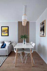 a white dining room with a table and a couch at Apartament Molo Olsztyńska Nad Morzem in Gdańsk