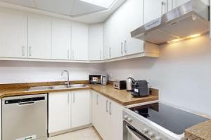 a kitchen with white cabinets and a sink at West Heights 1 - Vacationer in Dubai