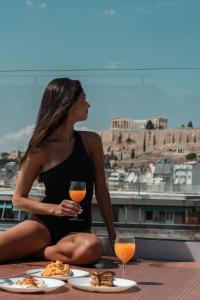 una donna seduta su un tavolo con un bicchiere di vino di Athesense Suites ad Atene