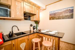 a kitchen with a sink and a counter with stools at Domek u Zosi in Zakopane