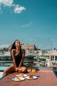 una mujer sentada en una mesa con comida y bebidas en Athesense Suites, en Atenas