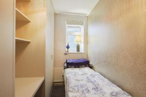 um pequeno quarto com uma cama e uma janela em A lovely and comfortable flat in South London em Thornton Heath