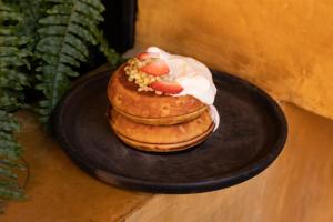 a stack of pancakes with strawberries on a black plate at Otro Oaxaca, a Member of Design Hotels in Oaxaca City