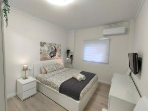 een witte slaapkamer met een bed en een televisie bij Non Stress Turia in Valencia