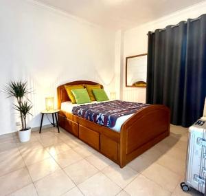 sypialnia z łóżkiem z zielonymi poduszkami i walizką w obiekcie CASA COSY - Caparica Beach and Surf Apartment w Costa de Caparica