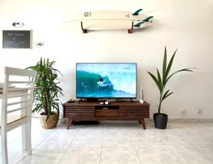 a living room with a tv and a surfboard on the wall at CASA COSY - Caparica Beach and Surf Apartment in Costa da Caparica