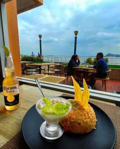 a plate of food with a bowl of salad and a bottle of beer at Ecusuites vista Río Jacuzzi Privado Wyndham 802 in Guayaquil