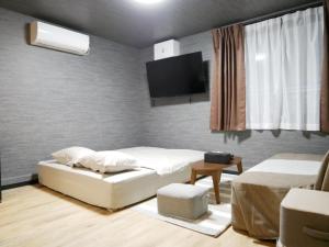 um quarto com uma cama e uma televisão na parede em HOOD - Vacation STAY 46047v em Amami