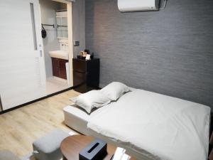 a bedroom with a bed and a table and a bathroom at HOOD - Vacation STAY 46466v in Amami