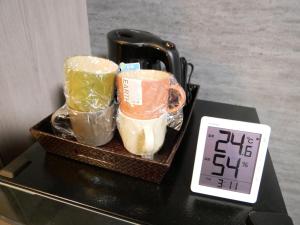 a tray with two cups on a table next to a clock at HOOD - Vacation STAY 46466v in Amami