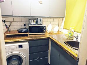 a kitchen with a washing machine and a microwave at Beautiful 1-Bed House in Leeds in Leeds