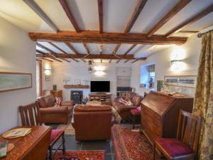 een woonkamer met lederen meubels en een televisie bij Naunton Cottage in Lyme Regis