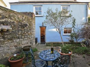 een tafel en stoelen voor een blauw huis bij Naunton Cottage in Lyme Regis