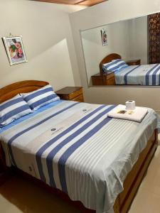 1 dormitorio con 2 camas con rayas azules y blancas en HOSTAL LOS NOGALES en Aguaytía