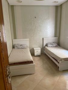a bedroom with two beds and a night stand at B 2 bedroom apartment in Fez