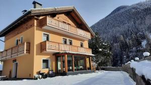 a large building with wooden balconies in the snow at B&B B&Beautyfol Dolomites adults only in Predazzo
