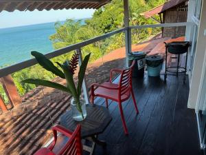 un portico con sedie, una pianta in vaso e l'oceano di Casa com vista a praia da Barra do Sahy a Barra do Sahy