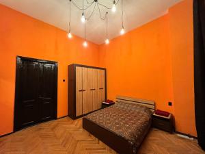 Schlafzimmer mit orangefarbenen Wänden, einem Bett und einem Kronleuchter in der Unterkunft KyivHome Loft on Maidan Independence Square in Kiew