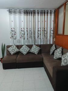 un sofá marrón con almohadas en la sala de estar en Departamento 4 camas 3 hab en Tacna