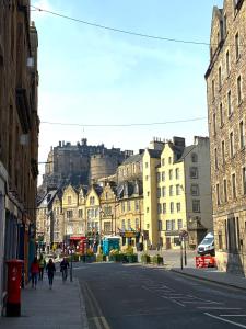 people walking down a city street with a castle in the background at Greyfriars Studio Edinburgh in Edinburgh
