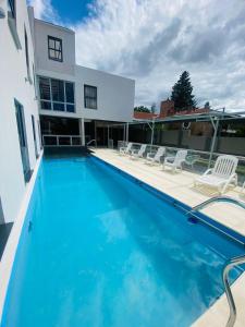 a swimming pool with chairs and a house at Ranqueles in Villa Carlos Paz