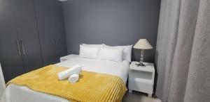 a bedroom with a white bed with a yellow blanket at Penzance by the beach in Durban