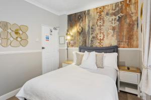 トーキーにあるKethla Houseの白いベッドと壁に絵画が飾られたベッドルーム1室