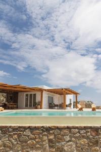 a house with a swimming pool and a stone wall at Birdhouse Private Luxury Suite in Agios Ioannis Mykonos